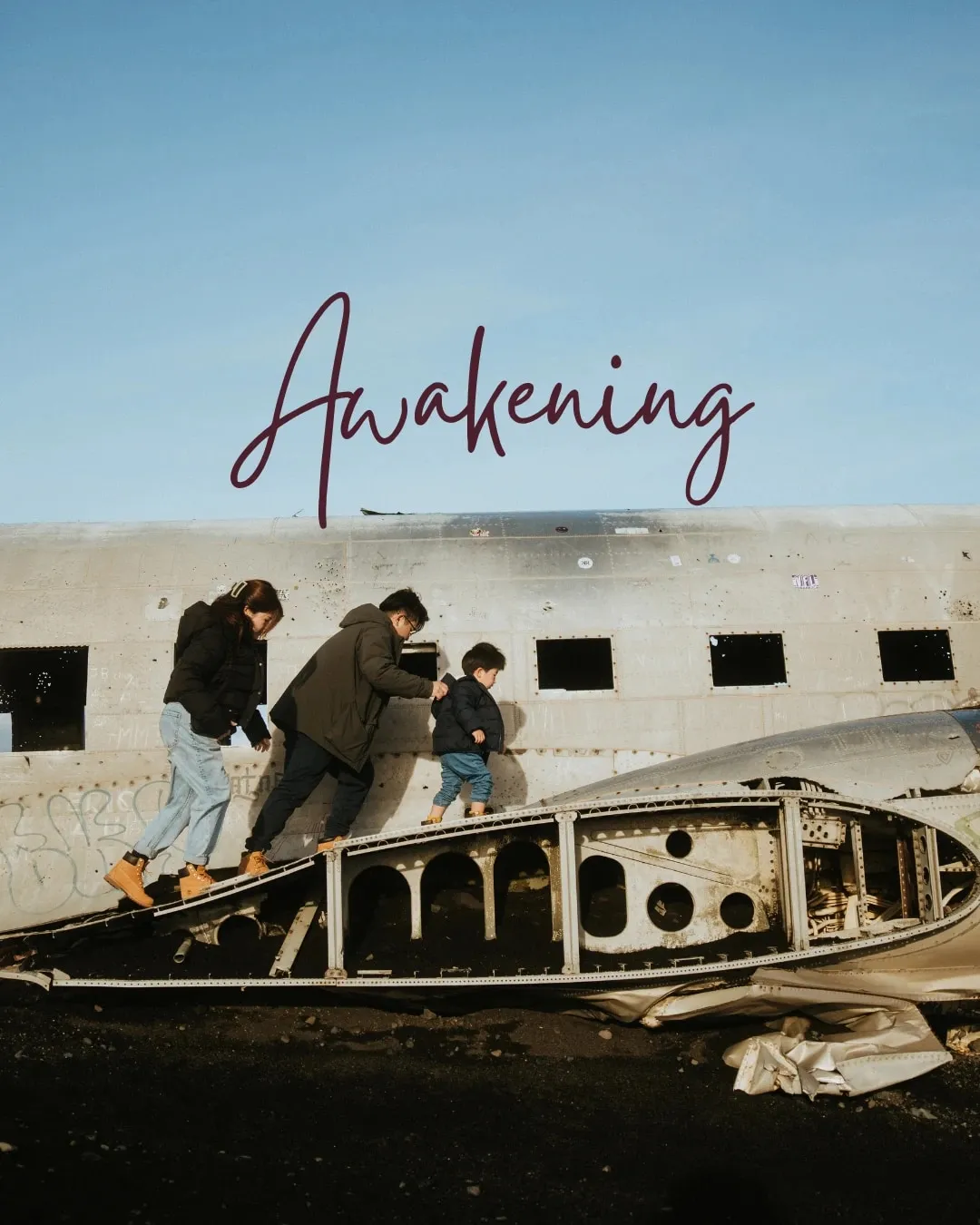 A woman, a man and a small boy climbing the wreck of an old plane under a blue sky, with the word Awakening written in script above them