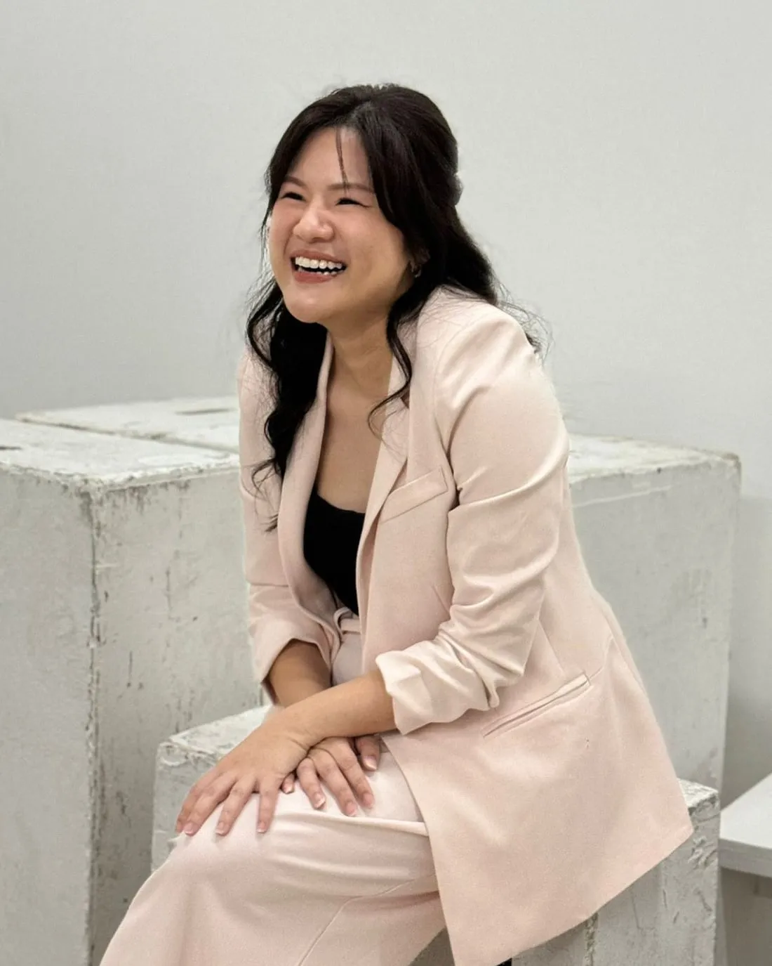 Shermene laughing, in a soft pink suit